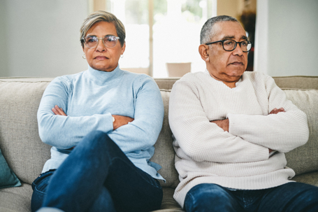 older couple sitting on a couch with their arms crossed